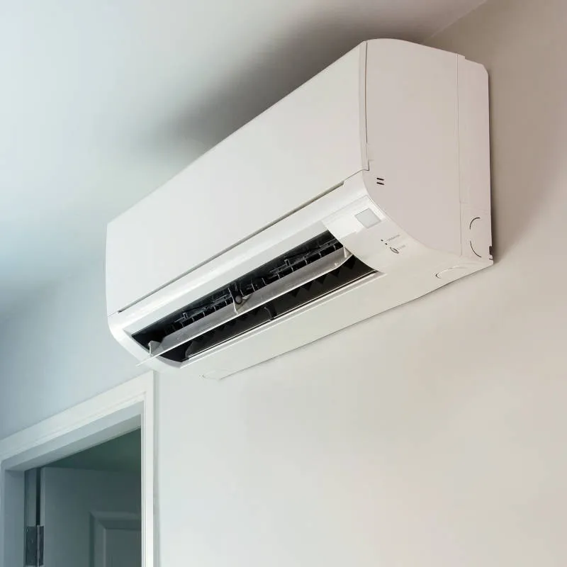 A white wall-mounted air conditioner unit above a doorway in a modern, light-colored room.